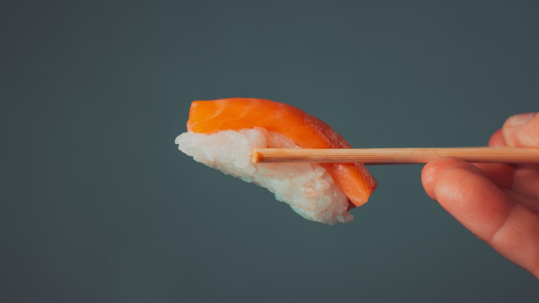 chopsticks holding salmon nigiri