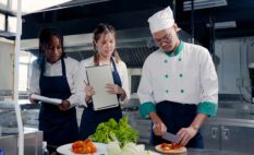 three chefs, one of them is slicing vegetables