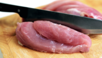 raw chicken on a cutting board with a knife
