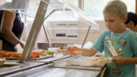 child getting food in line in cafeteria