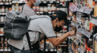 man bent over to inspect food label on low shelf at grocery store