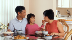 mother father and young daughter eating dinner with rice on the table