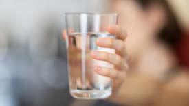 person holding up glass of water