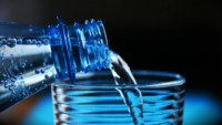 Close-up of Bottle Pouring Water into Glass