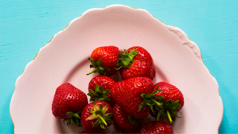 aerial view of plate of strawberries on blue table