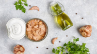 canned tuna in oil next to jar of oil and garlic cloves