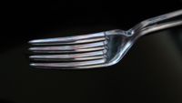 clear plastic fork against black background