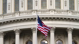 close up of U.S. Capitol Hill dome with U.S. flag in foreground