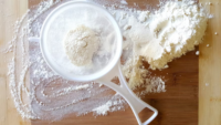 flour in a sifter on wood surface