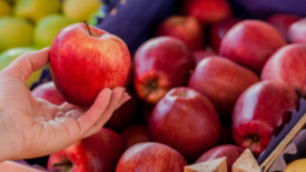 hand holding a shiny apple at store