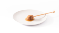 honey wand and puddle of honey on a white plate