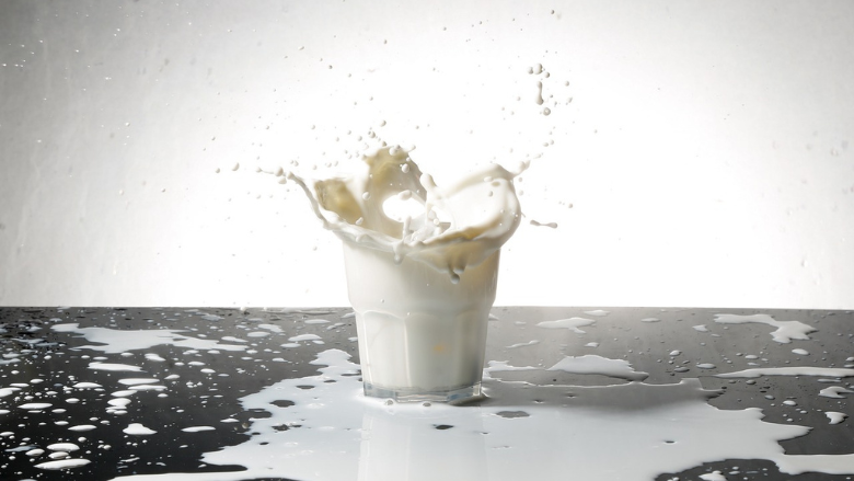 milk splashing out of glass all over table