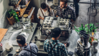 overhead shot of customers buying coffee at cafe with baristas working behind counter