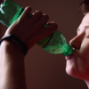 person drinking from soda bottle