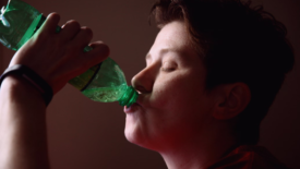 person drinking from soda bottle