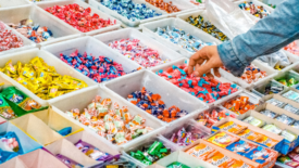 person reaching hand into assortment of candy display at store