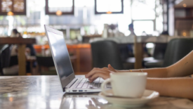 person using laptop coffee cup in foreground