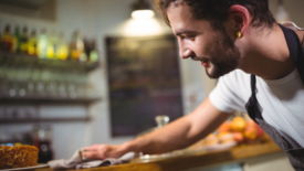 person wiping counter with cloth in cafe