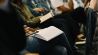 row of professionals seated at conference with open notebooks