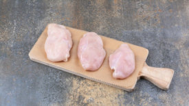 three raw chicken breast on cutting board