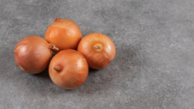 whole yellow onions on gray surface