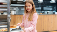 young girl getting tray of food in school cafeteria