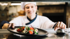 cook serving up salad in kitchen