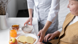 elderly woman being served meal on a tray