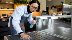 employee disinfecting table at restaurant