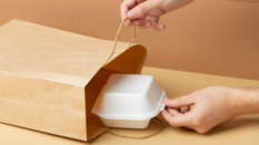 hand pulling Styrofoam food container out of paper bag