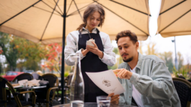 man looking at menu ordering food at cafe