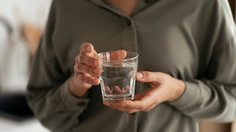 person holding glass of water in both hands