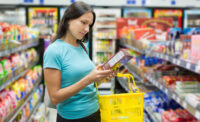 woman examining label of boxed food in grocery store