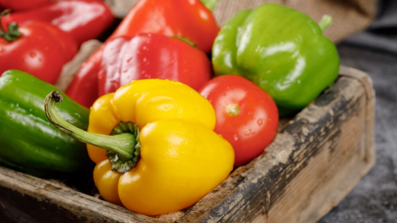 green yellow and red bell peppers in wooden crate