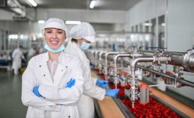 young person smiling at camera working in fruit processing facility